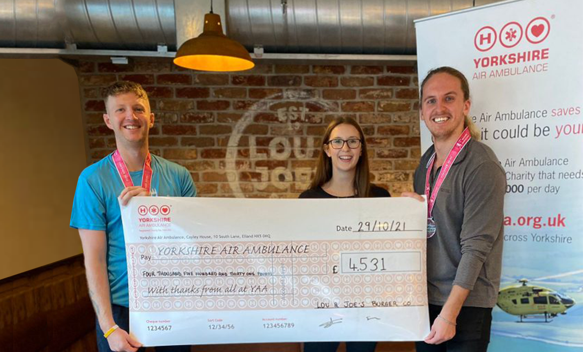 Photo of Louie from Lou and Joe's Burger Company presenting a cheque to Vicki and Scott from Yorkshire Air Ambulance