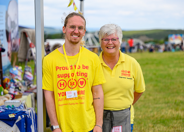 Two Yorkshire Air Ambulance volunteers wearing yellow t-shirts which say 'Proud to support' and have the Yorkshire Air Ambulance logo