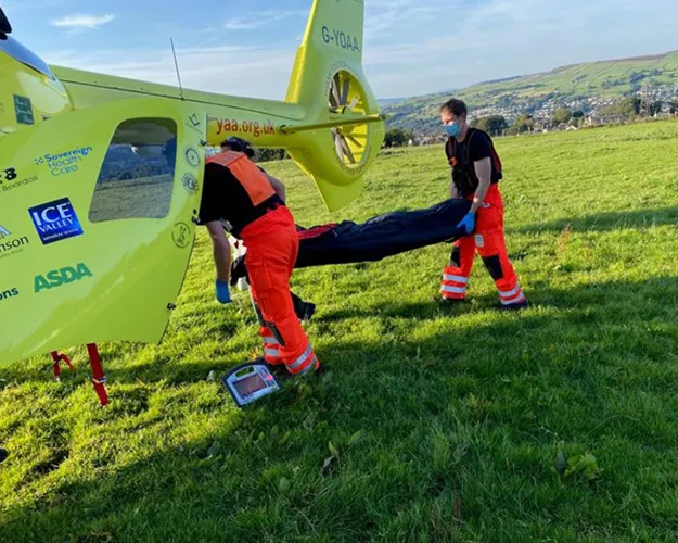 Photo of Sophie Shaw on a stretcher, being lifted in to the back of an air ambulance by two members of the Yorkshire Air Ambulance crew