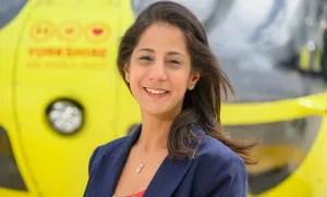 Photo of Yorkshire Air Ambulance Grants & Trusts Manager Marianne Haworth stood in front of one of the yellow Yorkshire Air Ambulance helicopters