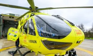 Close up image of the front of a yellow helicopter, which is sat on a helipad. 