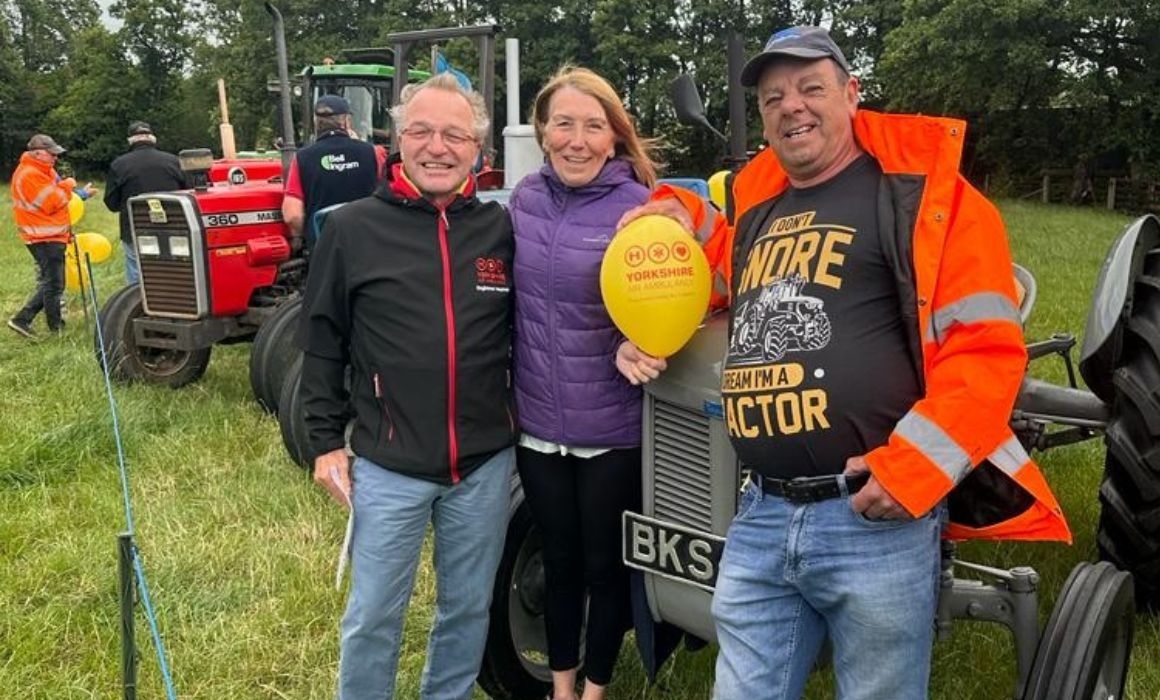 two men and a woman next to a tractor