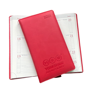 One closed red diary say on top of another open diary.