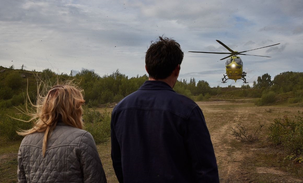 two people looking at a helicopter in the sky