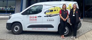 Two women standing in front of a white van which has a picture of a yellow helicopter on it and the Yorkshire Air Ambulance logo.