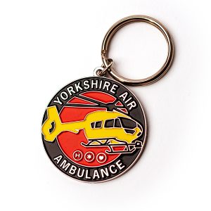 A round metal keyring featuring a yellow aircraft on a red background with the words YORKSHIRE AIR AMBULANCE