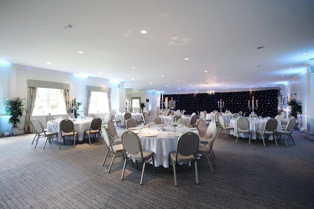 An event space with round tables covered in white table cloths, set out for dinner. 